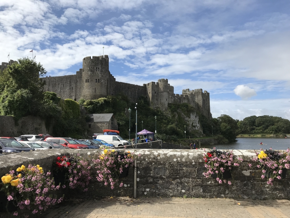 Château ancien avec des fleurs et des voitures garées.