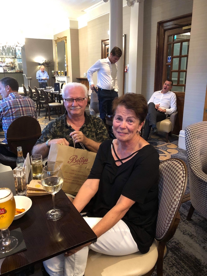 Deux personnes assises à une table avec des boissons et un sac.