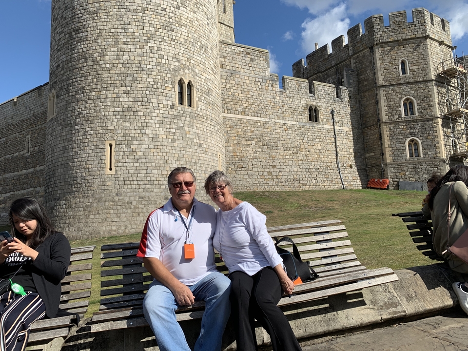 Couple assis sur un banc devant un château.