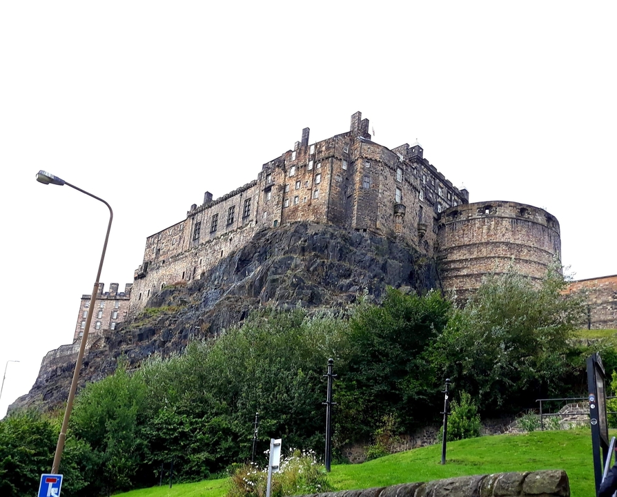 Un château de pierre sur une colline entouré de verdure.