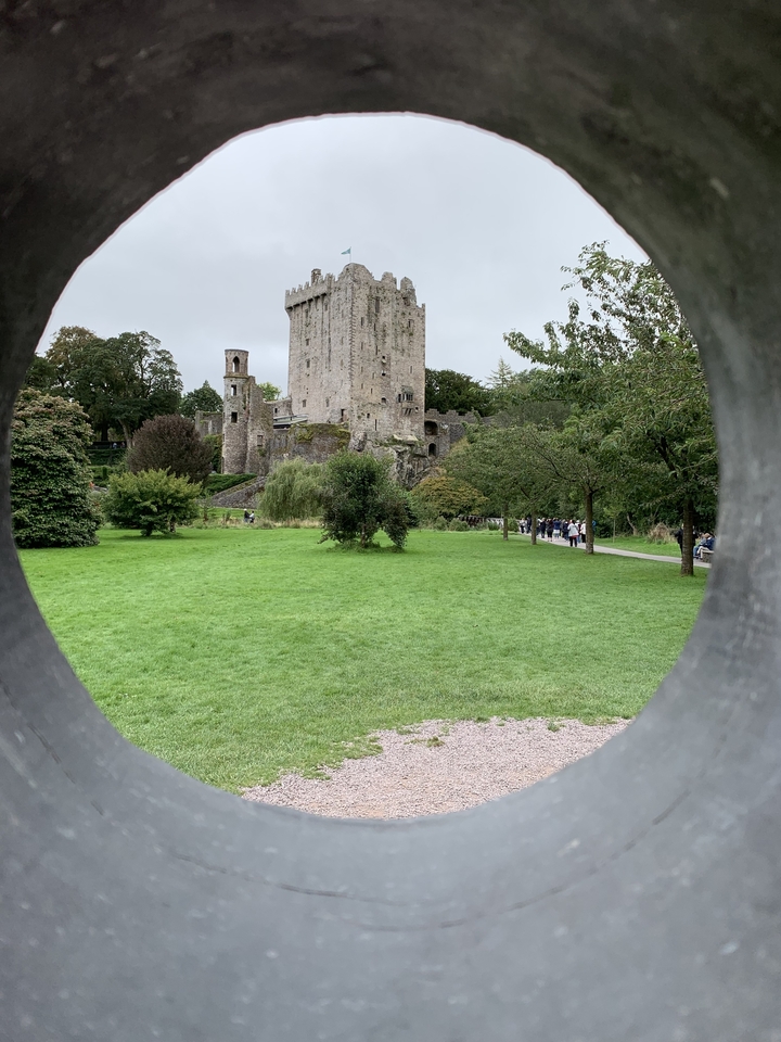 Château vu à travers un cadre circulaire avec des personnes et un jardin.