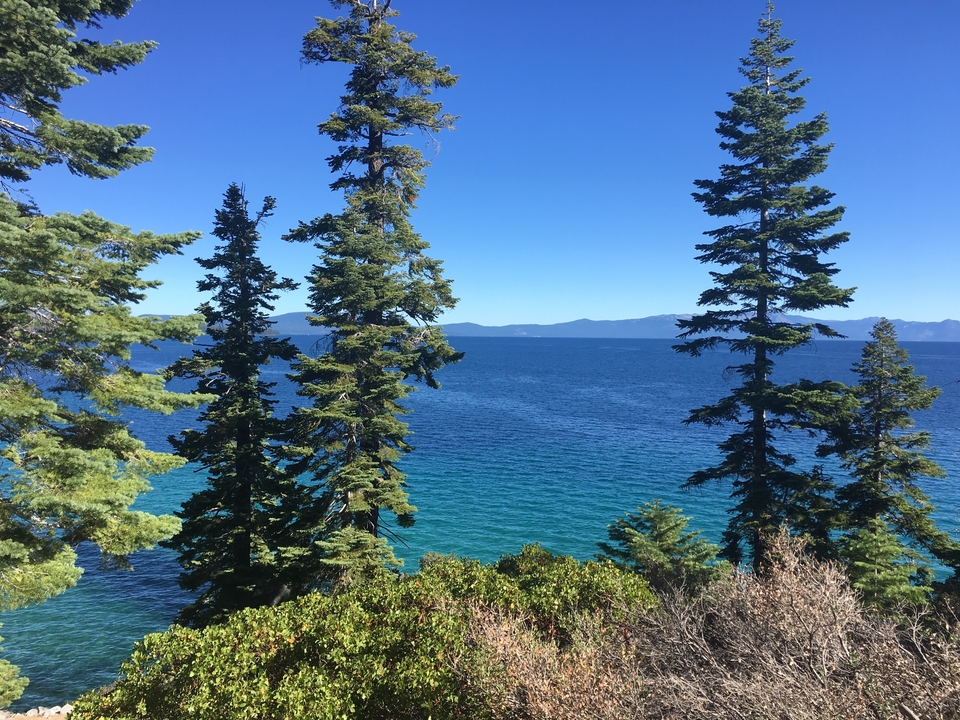Lac limpide avec une vue sur des chaînes de montagnes en arrière-plan.