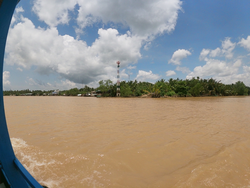 Rivière large avec des bâtiments épars et une tour de communication.