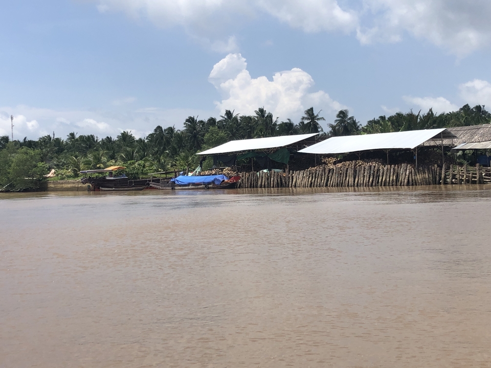 Scène de bord de rivière avec bateaux et structures en bois.