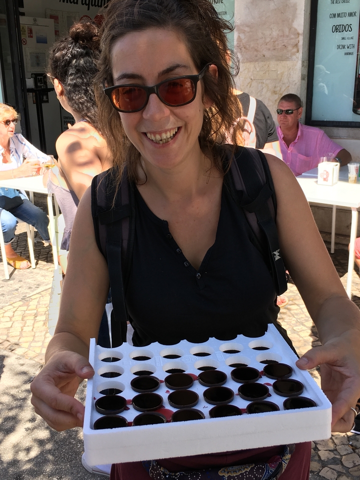 Une femme tenant une pâtisserie avec des personnes assises en arrière-plan.