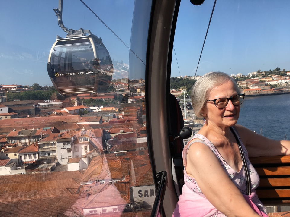 Une femme à l'intérieur d'un téléphérique avec une vue sur la ville et la rivière à l'extérieur.