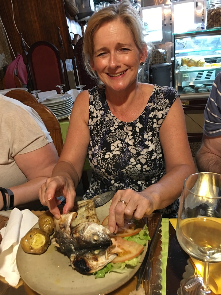 Gros plan d'une femme assise à une table avec de la vaisselle et un verre de vin.