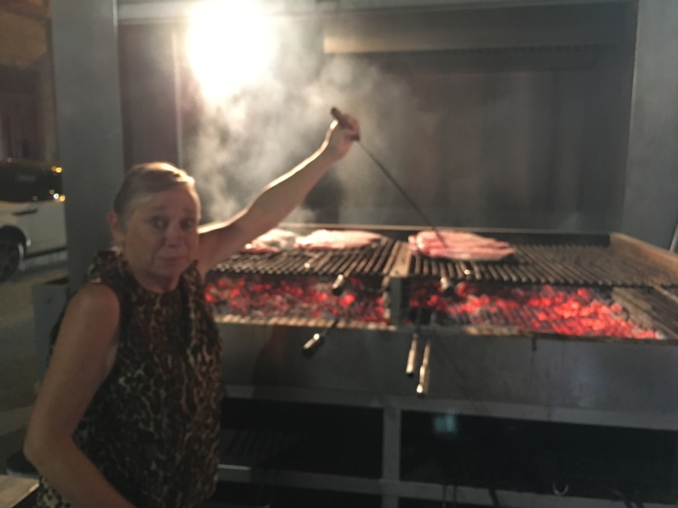 Une femme qui fait griller de la nourriture sur un barbecue extérieur avec de la fumée qui s'élève.