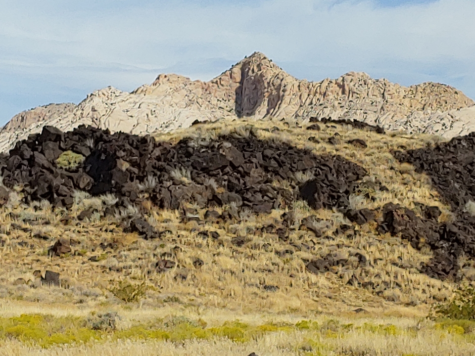 Paysage désertique avec des collines rocheuses et un ciel pâle.