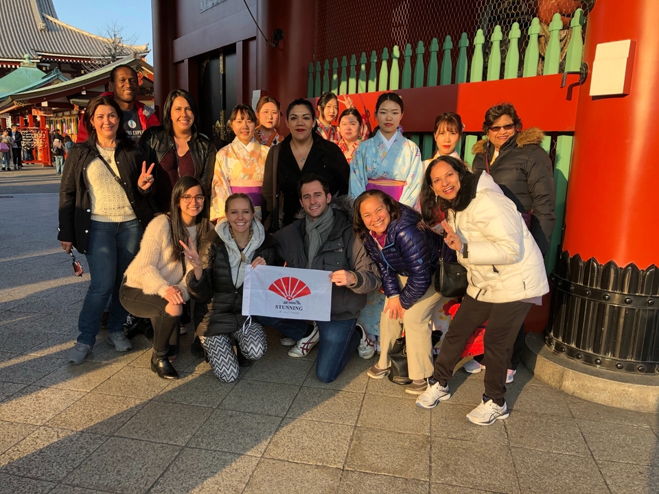 Groupe de personnes posant avec un drapeau devant un temple.