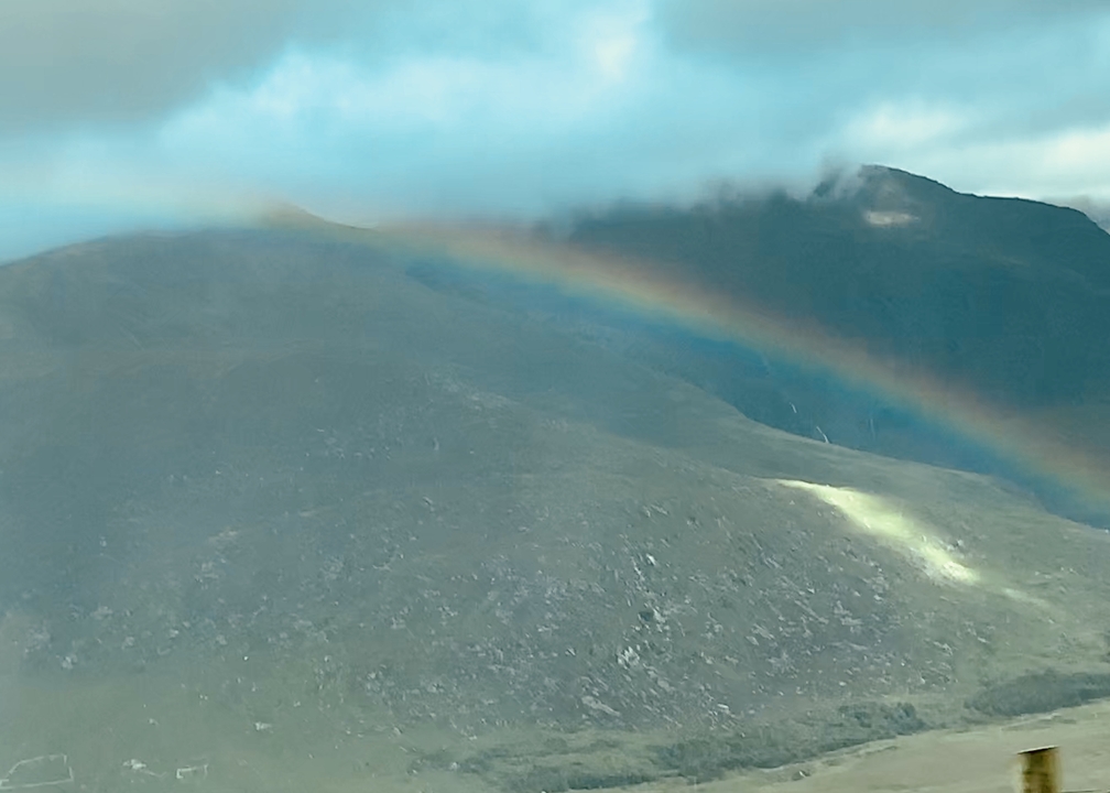 Arc-en-ciel s'arquant au-dessus d'un paysage de colline.