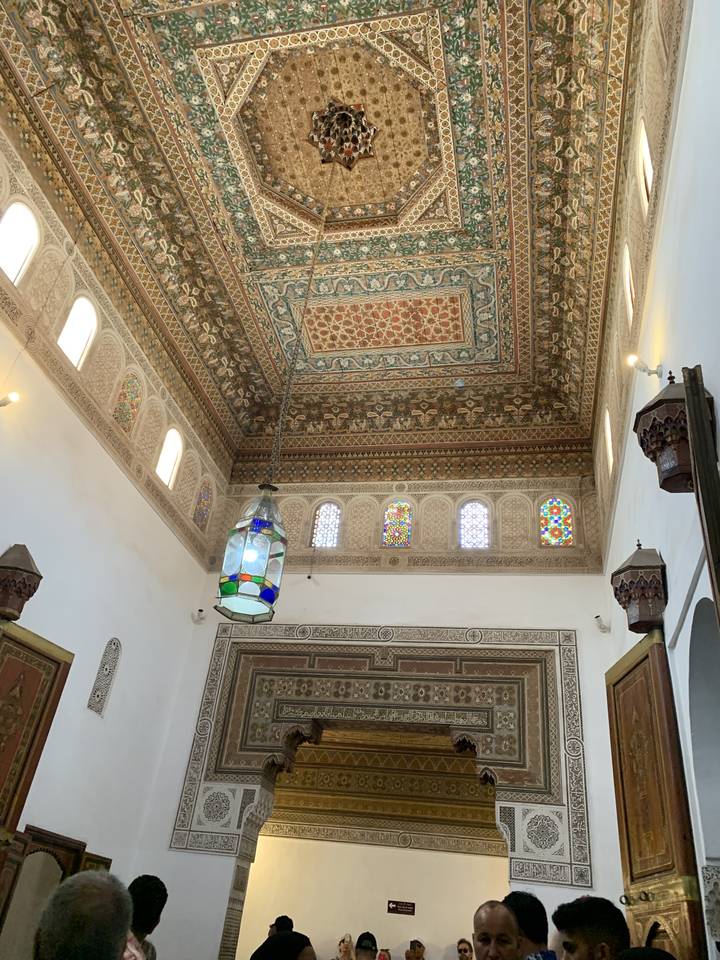 Plafond marocain richement décoré avec des personnes qui l'observent.