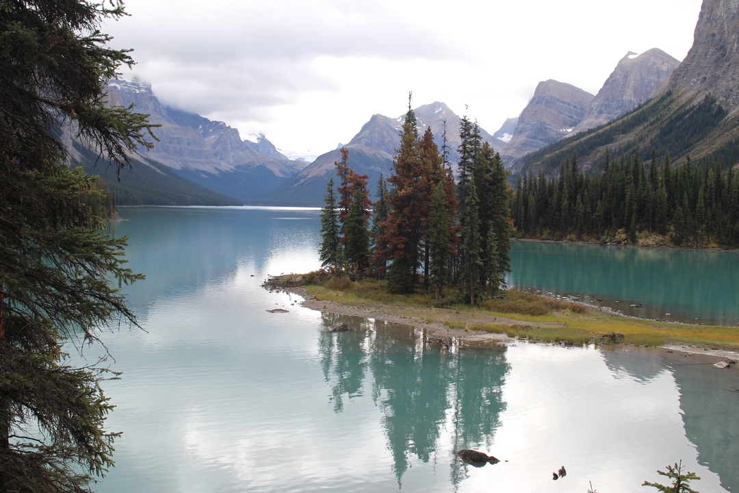 Île dans un lac turquoise entourée de montagnes.