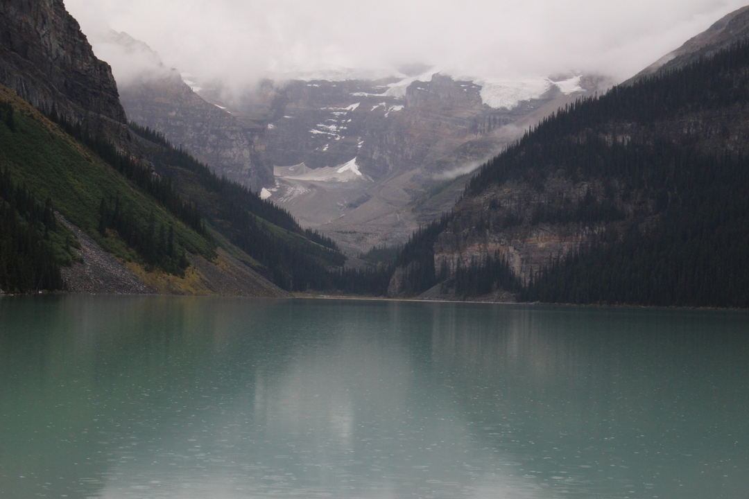 Lac serein avec montagnes et brume en arrière-plan.