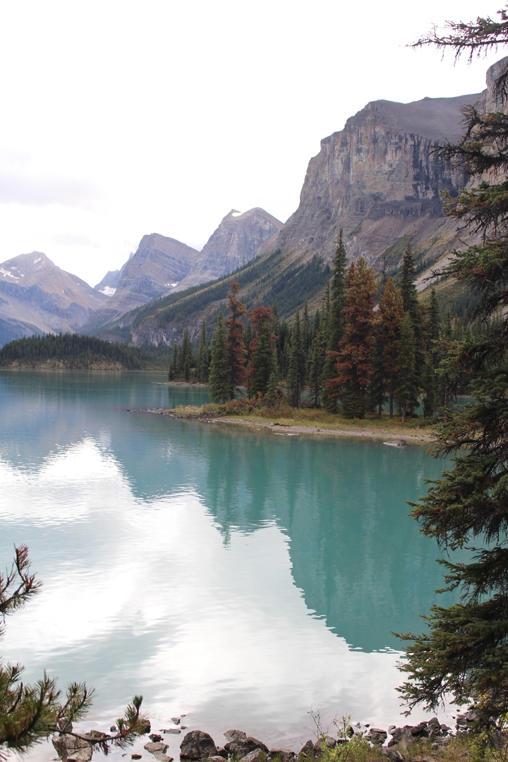 Lac turquoise avec forêt et montagnes.