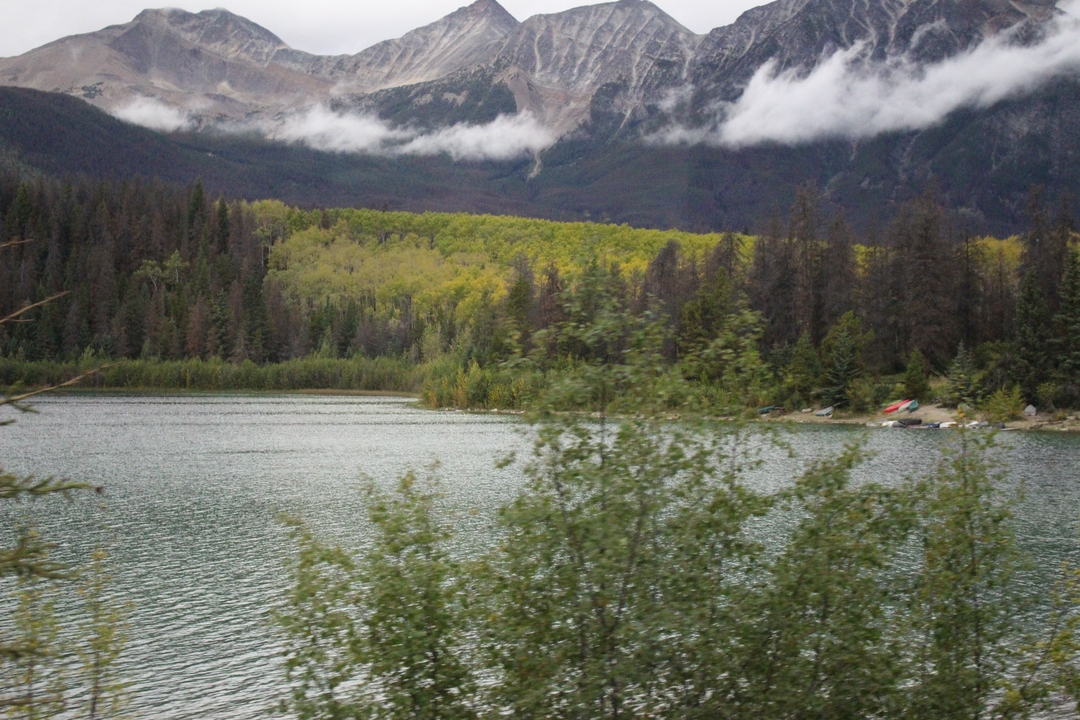 Lac avec forêt environnante et montagnes en arrière-plan.