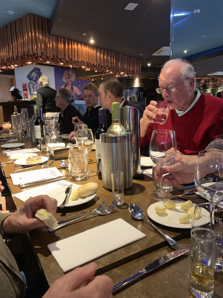 Groupe de personnes dînant avec des bouteilles de vin sur la table.