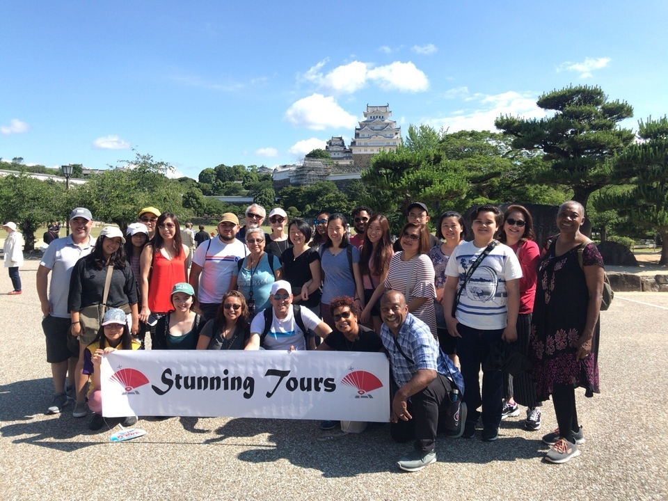 Groupe de touristes devant un château japonais historique.