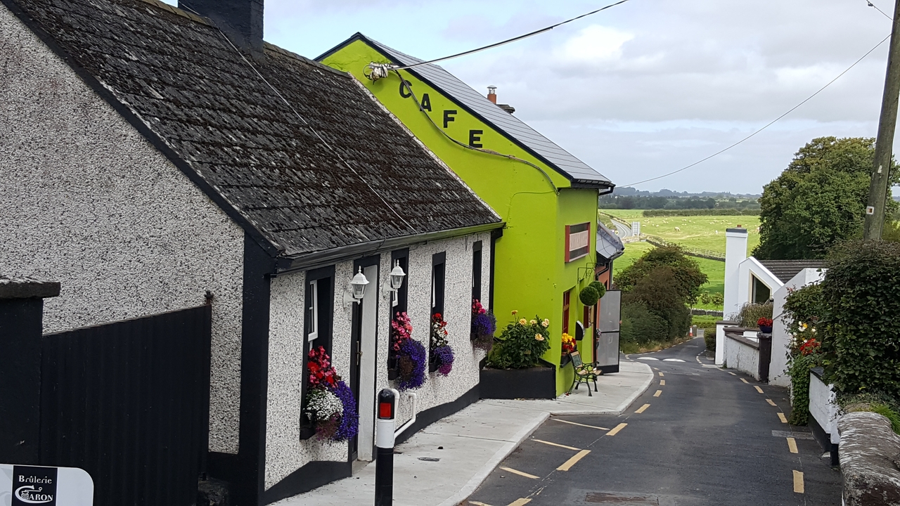 Café coloré dans une rue étroite avec des décorations florales.