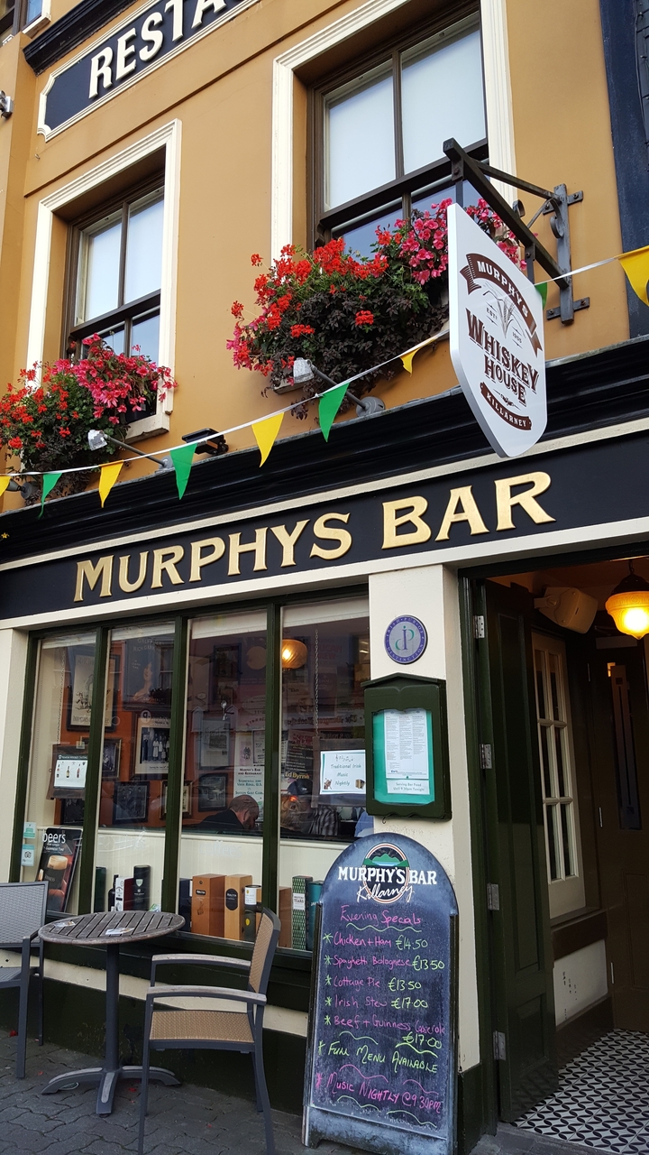Extérieur d'un bar avec des drapeaux suspendus et une signalétique.