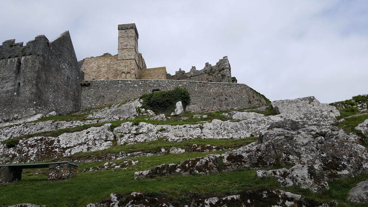 Fortification de pierre sur une colline rocheuse sous un ciel nuageux.