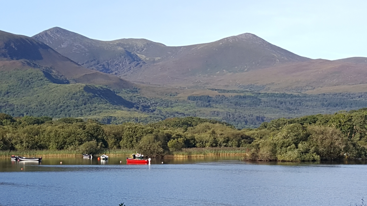 Un lac pittoresque avec des bateaux et un décor montagneux en arrière-plan.