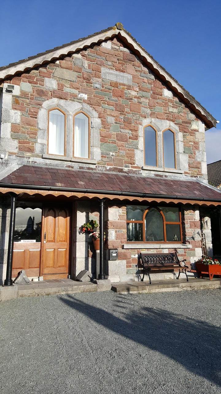 Façade d'immeuble en pierre avec des pots de fleurs et un panneau de chambre libre.