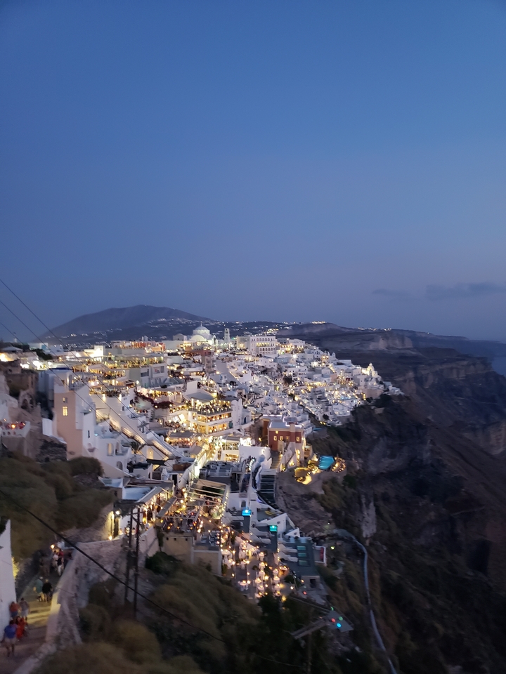 Paysage urbain avec des bâtiments regroupés sur une colline, pris au crépuscule.