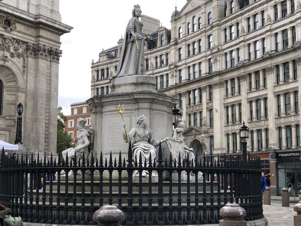 Statue représentant un trident et plusieurs figures dans un cadre urbain.