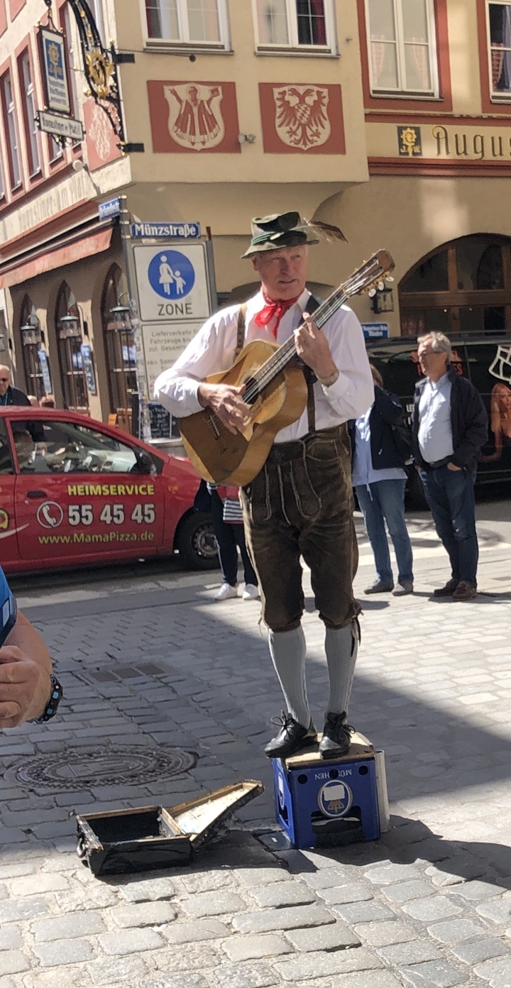 Personne en tenue traditionnelle jouant de la guitare dans la rue.