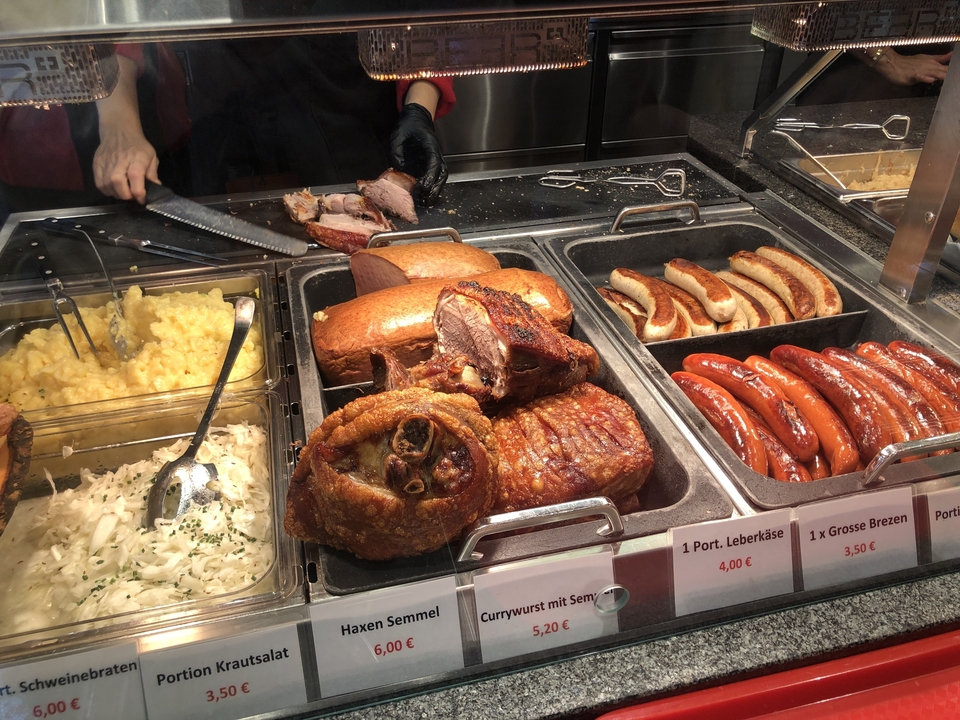 Étalage de diverses viandes cuites dans un marché alimentaire.