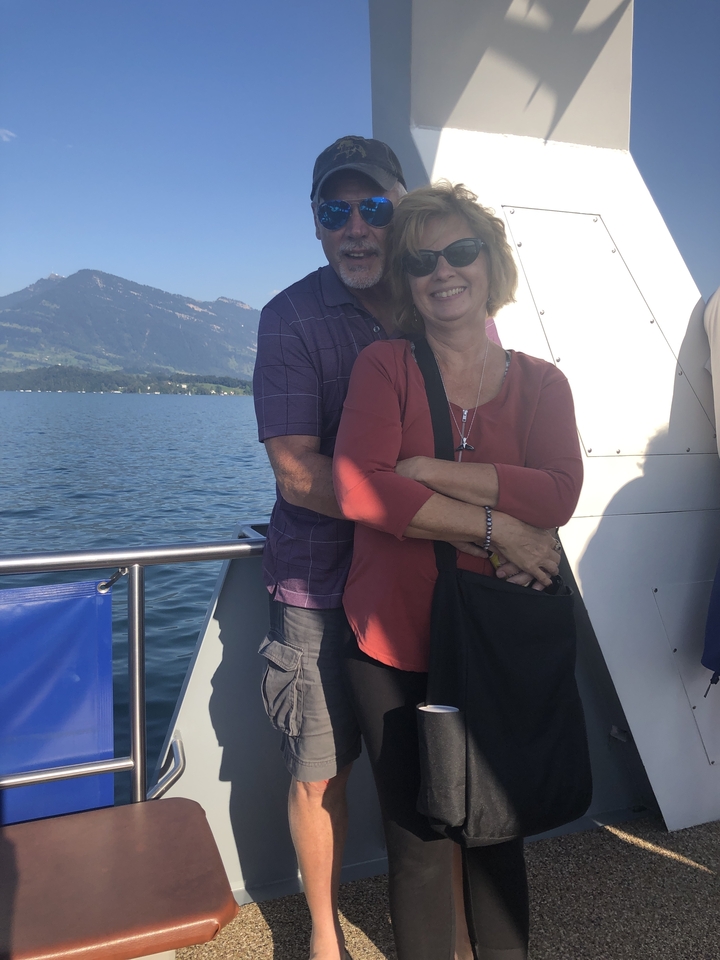 Deux personnes qui posent avec une vue panoramique sur un lac et les montagnes.