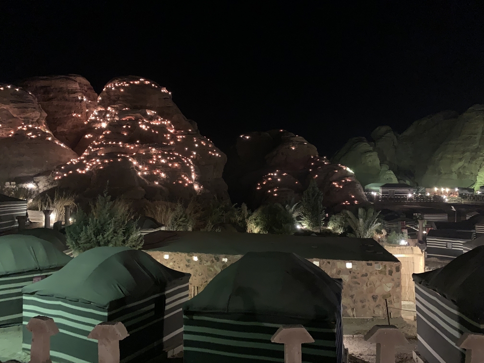 Vue nocturne de montagnes et de tentes illuminées par des lumières.