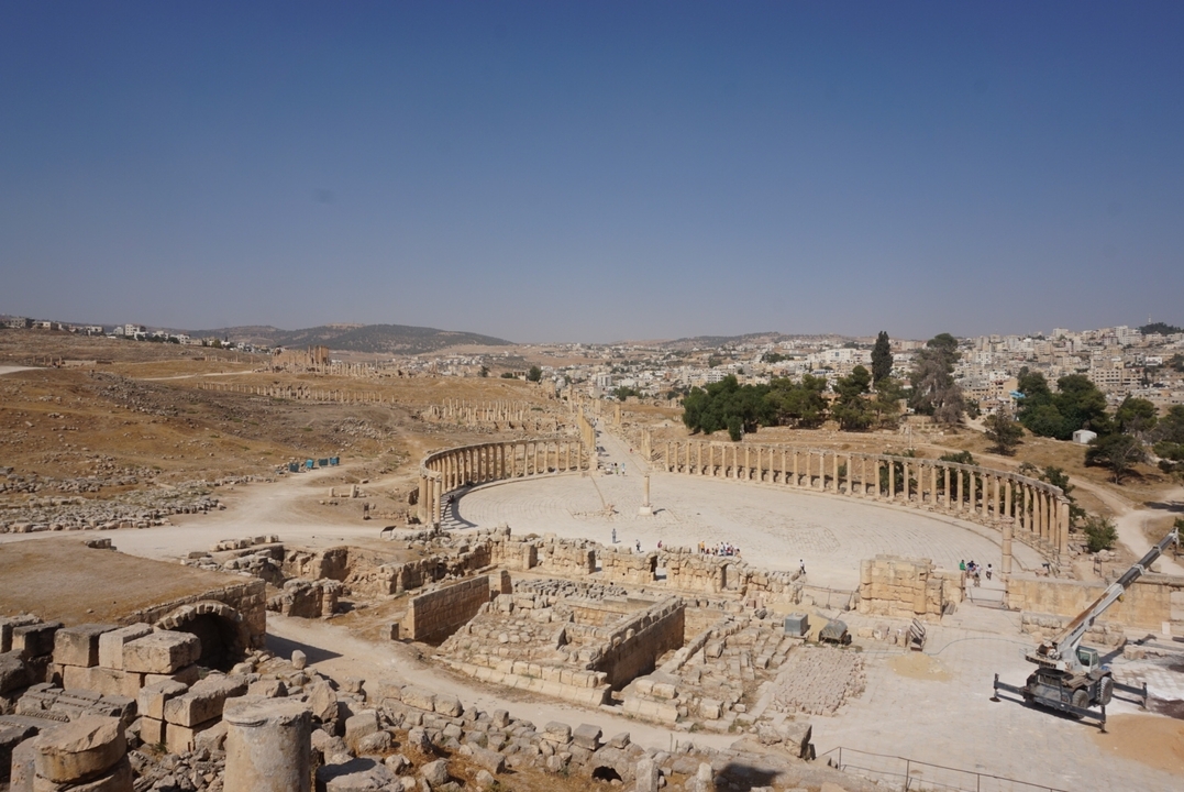 Ruines d'une ville antique avec une place ovale et des colonnes de pierre.