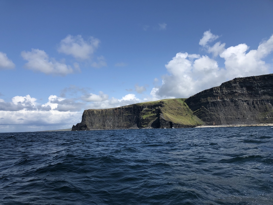 Falaises de Moher depuis l'océan avec un ciel bleu.