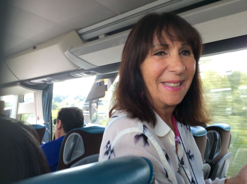 Femme souriante dans un bus ou un train en mouvement.