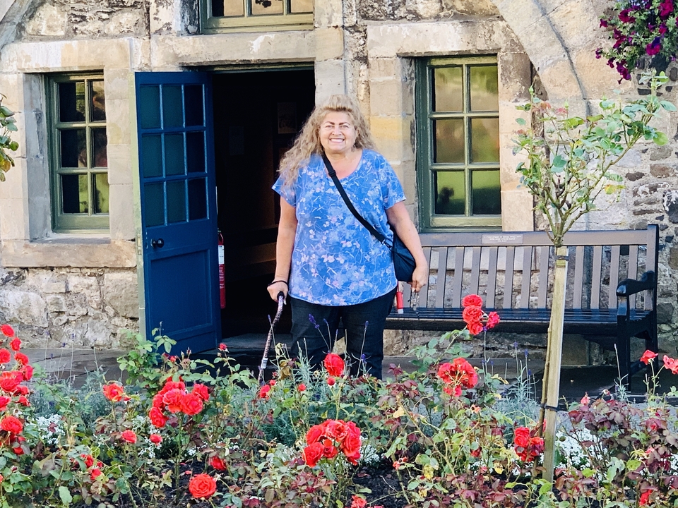 Personne souriante debout au milieu d'un jardin avec des fleurs rouges éclatantes.