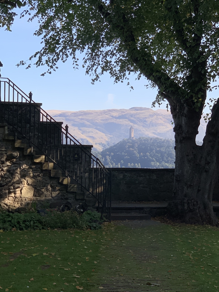 Une vue lointaine d'une tour sur une colline encadrée par des balustrades en fer.