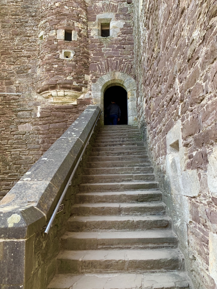 Personne montant des marches en pierre dans une structure historique.