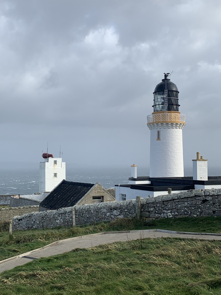 Phare blanc surplombant l'océan sous un ciel nuageux.