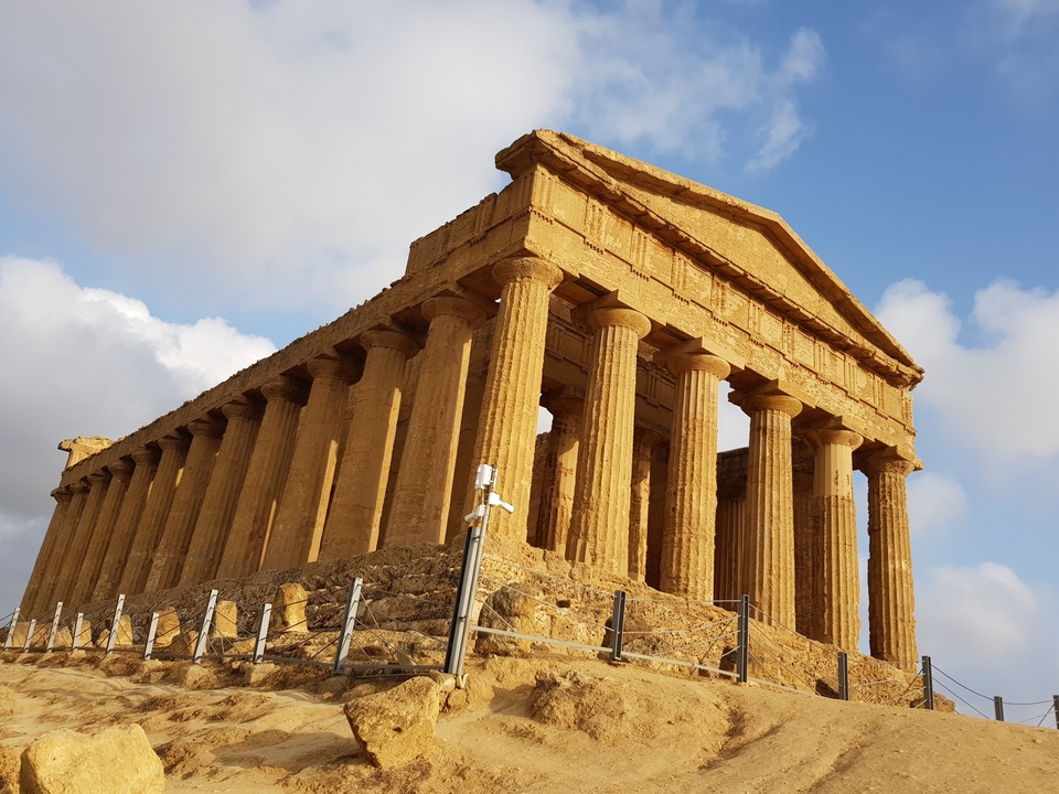 Un temple antique bien conservé avec de hautes colonnes sous un ciel dégagé.