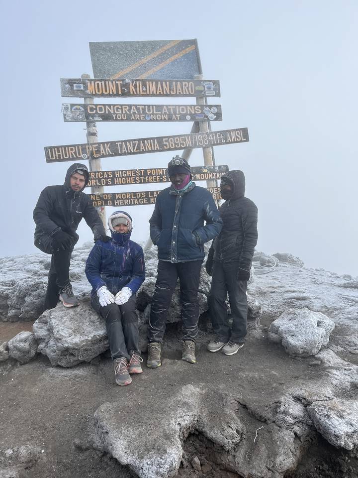 Quatre personnes posant au sommet d'une montagne avec de la neige.