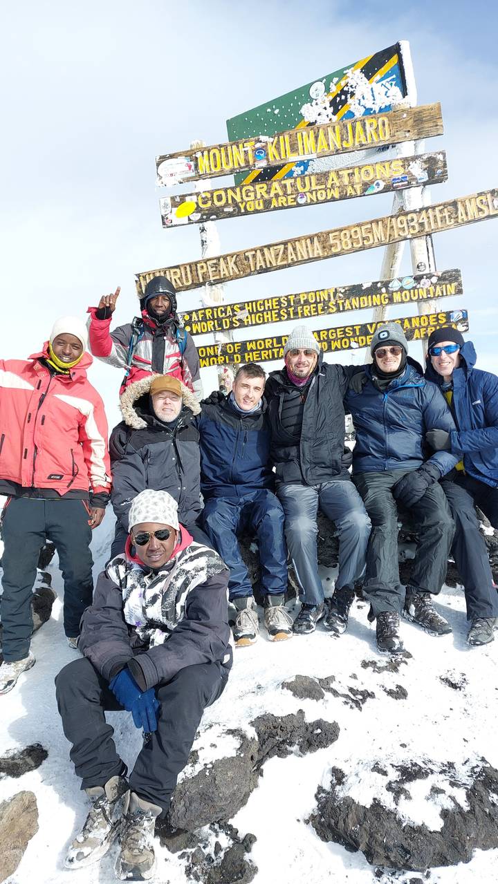 Groupe de personnes posant devant un panneau du sommet du Kilimandjaro.