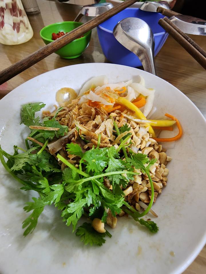 Assiette de nourriture vietnamienne avec herbes et légumes.
