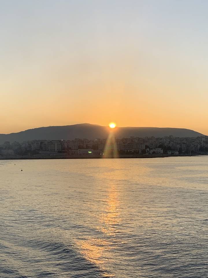 Vue du coucher de soleil sur la mer avec un littoral lointain.