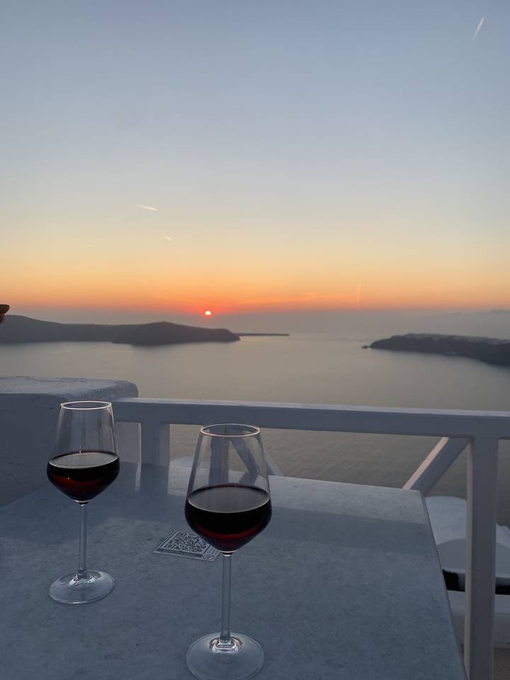 Des verres à vin sur une table avec vue sur un coucher de soleil.