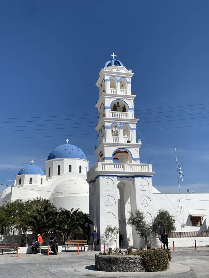 Église blanche avec clocher et dômes bleus.