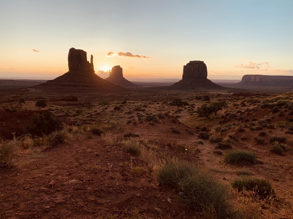 Coucher de soleil sur des formations rocheuses emblématiques dans un paysage désertique.