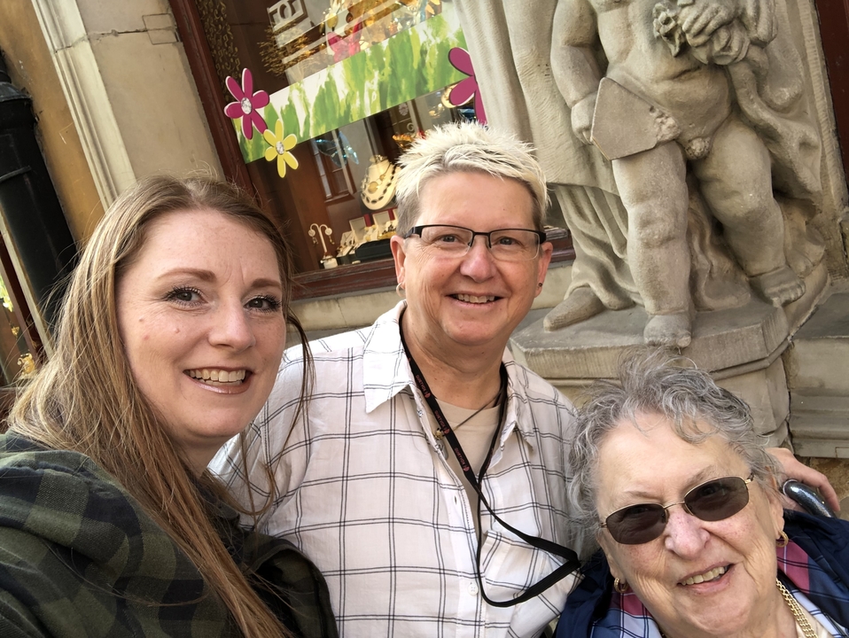 Trois personnes souriantes avec une statue en arrière-plan.