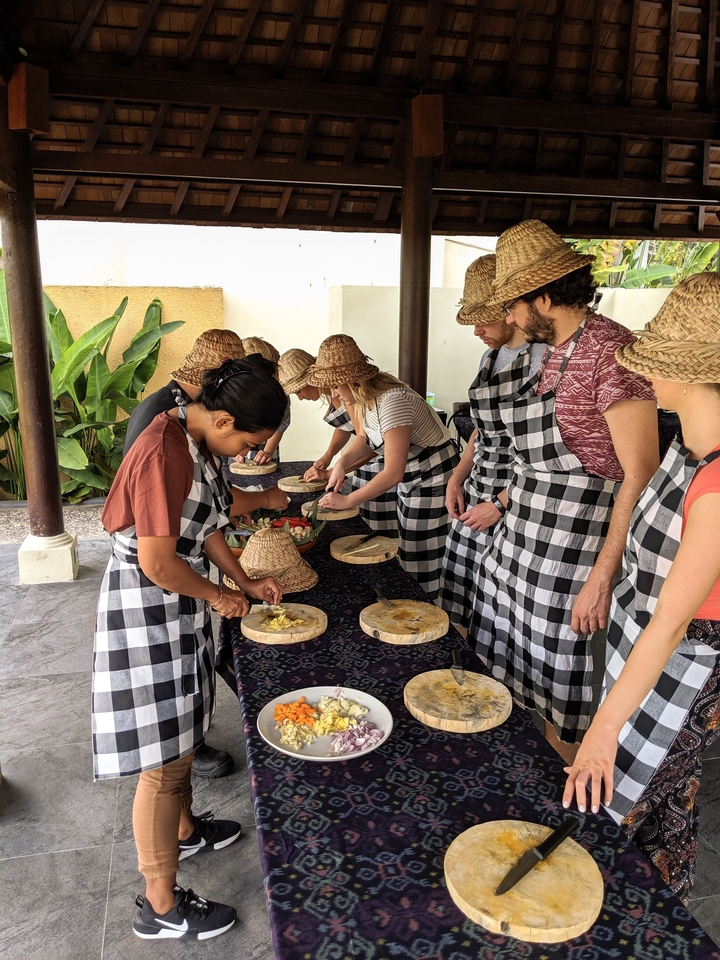 Cours de cuisine en groupe avec des participants en tabliers et toques.